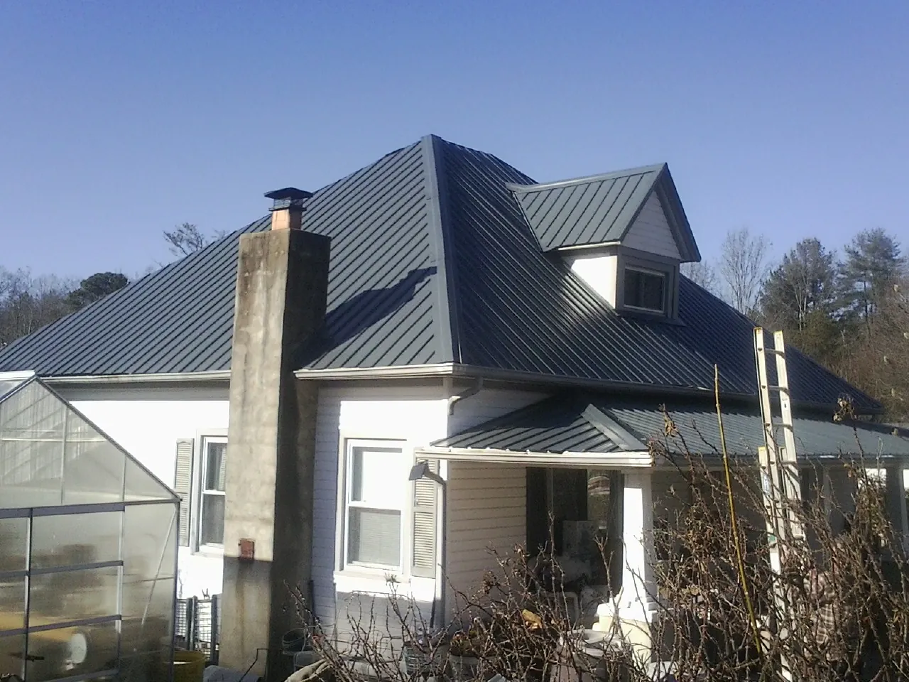 Dark blue standing seam metal roof on a white farmhouse with dormer — Slate & Tile Roof Repair by Roofing Brothers in Goreville