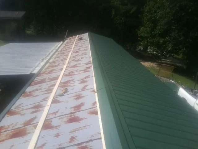Old rusted panels beside newly installed green metal roofing — Wind Damage Roof Repair by Roofing Brothers in Goreville