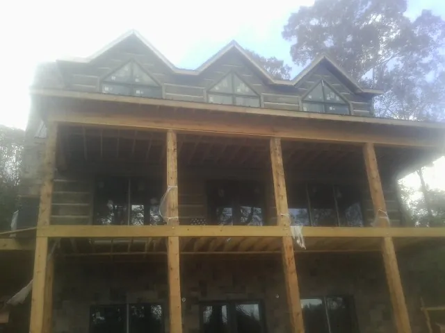 Dormers and porch framing on a large log home under construction — Roof Coating work by our crew in Goreville