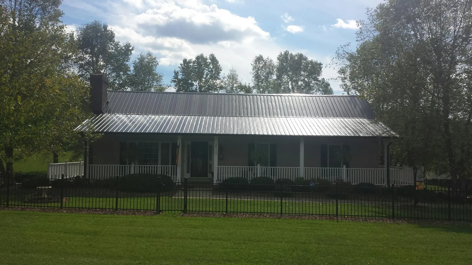 Gray metal roof on a brick ranch with a full width front porch — Gutter Guard Installation work by our crew in Goreville
