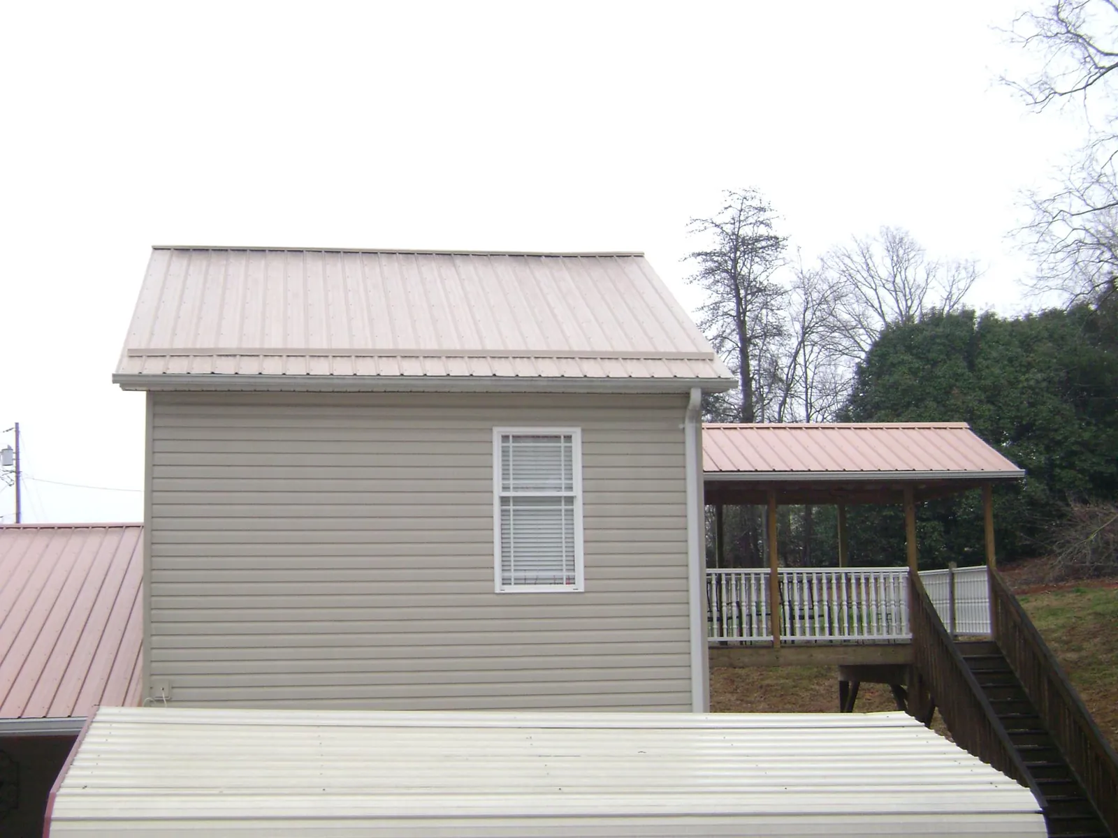 Tan metal roofs on a two story addition and attached porch, from a Roof Replacement job in Goreville