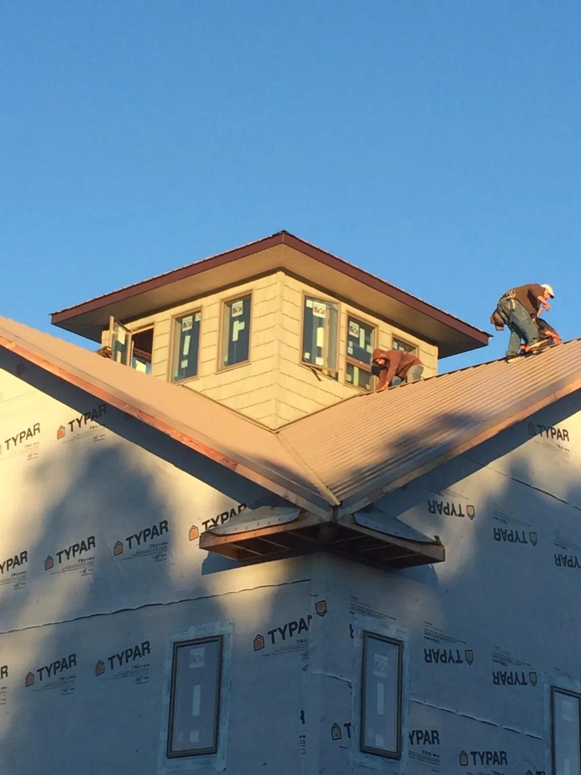 Roofers working around a rooftop cupola on a new metal roof at sunset — Roof Waterproofing in Goreville by Roofing Brothers